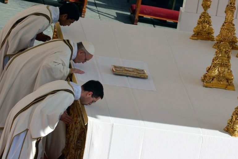El Papa Francisco y dos concelebrantes besan el altar antes de comenzar con la Eucaristía.