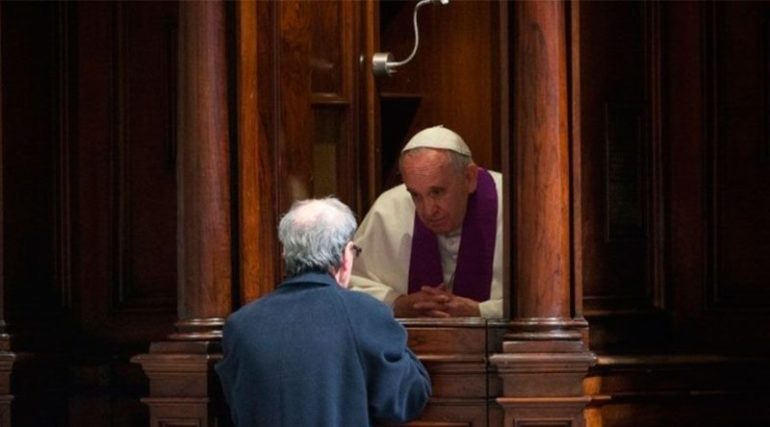 El Papa Francisco administra a un fiel el sacramento de la confesión desde un confesionario.