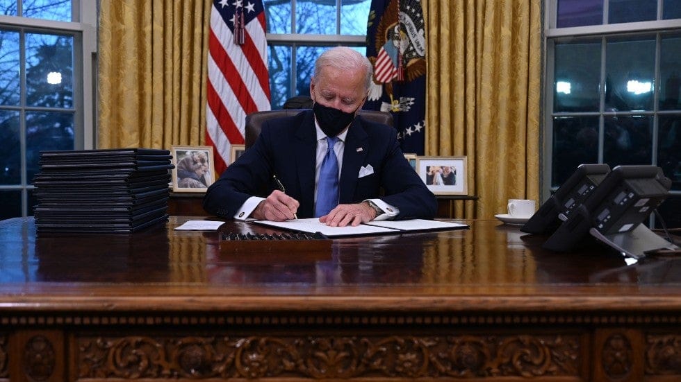 Biden firma sus primeras órdenes ejecutivas, con la imagen del Papa a su izquierda