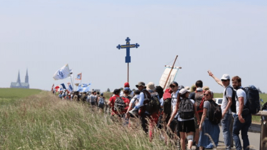 Peregrinos católicos marchando hacia Chartres con símbolos religiosos, expresión del ardor misionero en Francia