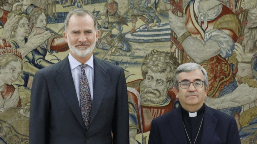 Rey de España como monarca católico junto a obispo en encuentro oficial