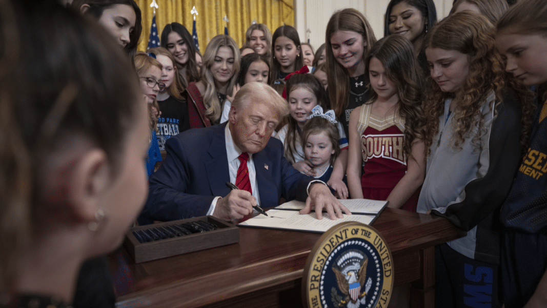 Trump firmando la orden ejecutiva rodeado de un grupo de mujeres
