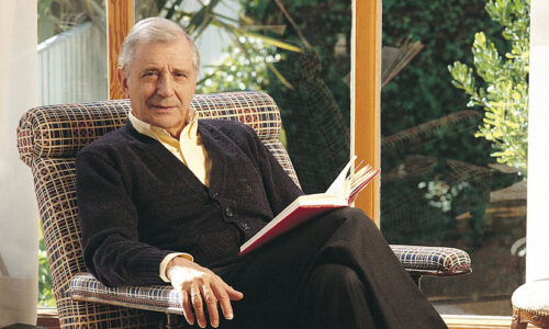 José Luis Olaizola sentado con un libro en las manos, en una sala luminosa