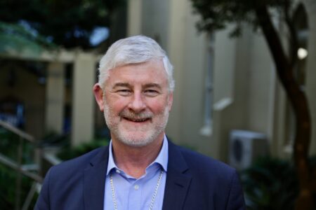 Shane Mackinlay sonriente en exteriores tras su nombramiento como arzobispo de Brisbane