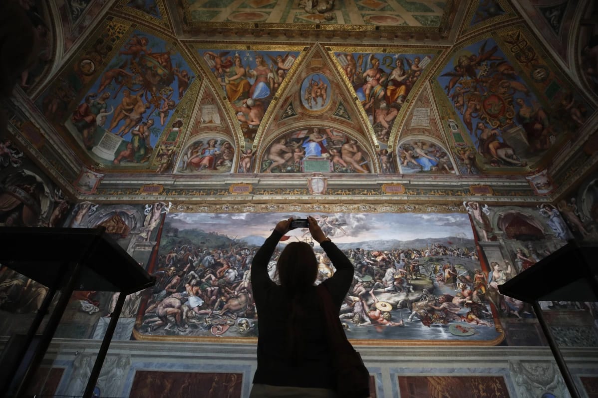 Visitante fotografiando la Sala de Rafael restaurada en los Museos Vaticanos.