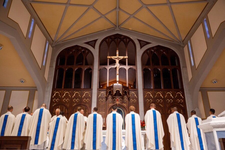 Sacerdotes recién ordenados en la Diócesis de Arlington durante la ceremonia frente al altar con un crucifijo