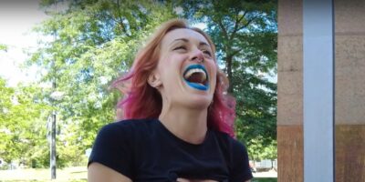 Una colaboradora de Pablo Iglesias riendo con el pelo teñido y los labios pintados de azul