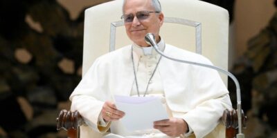 El Papa León XIV, símbolo en medio de la crisis de una Iglesia dividida, aparece sentado en su silla papal con sotana blanca y documentos en mano.
