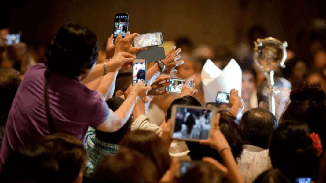 Feligreses tomando fotos durante un evento religioso, capturando momentos con sus teléfonos móviles, similar al Jubileo para influencers católicos.