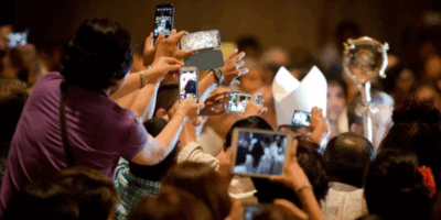Feligreses tomando fotos durante un evento religioso, capturando momentos con sus teléfonos móviles, similar al Jubileo para influencers católicos.