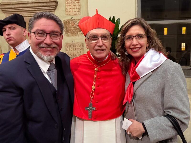 El cardenal Carlos Castillo Mattasoglio posa sonriente con dos personas durante un acto público