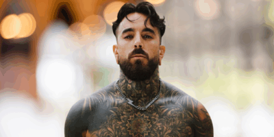 René ZZ tatuado mira al frente, protagonista del testimonio “Soñé que Dios me amaba”
