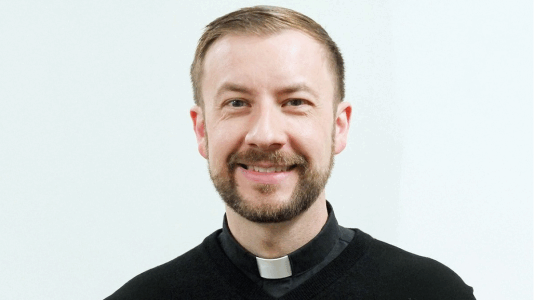 El nuevo obispo de Baker sonriente, con sotana y alzacuellos